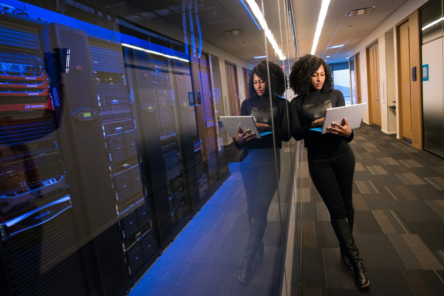 Two professionals with laptops in a data centre corridor